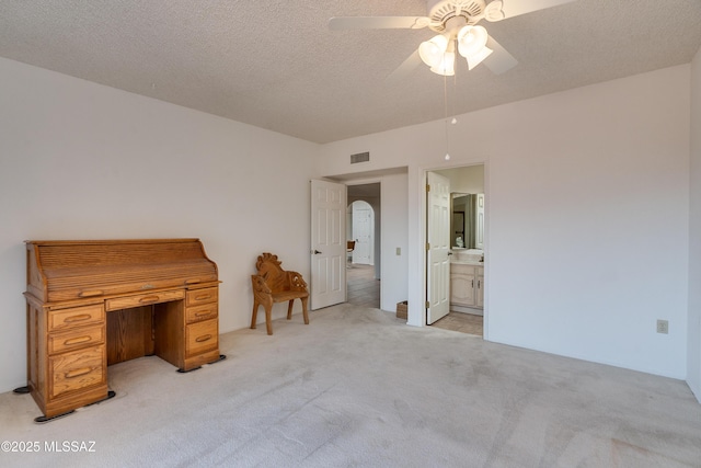 unfurnished bedroom with visible vents, a ceiling fan, light carpet, connected bathroom, and a textured ceiling