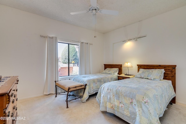 bedroom with ceiling fan, baseboards, a textured ceiling, and light colored carpet