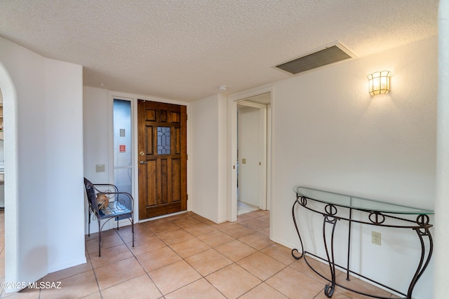 entryway featuring arched walkways, visible vents, a textured ceiling, and light tile patterned flooring