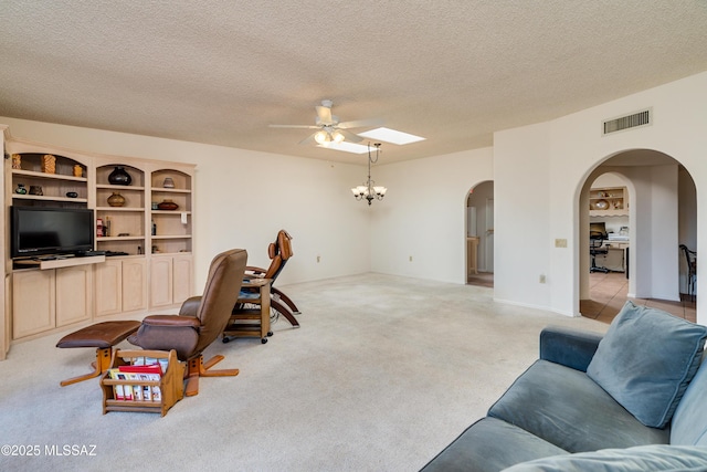 living room with visible vents, arched walkways, light colored carpet, a textured ceiling, and ceiling fan with notable chandelier