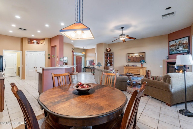 dining space with light tile patterned floors, a glass covered fireplace, visible vents, and recessed lighting