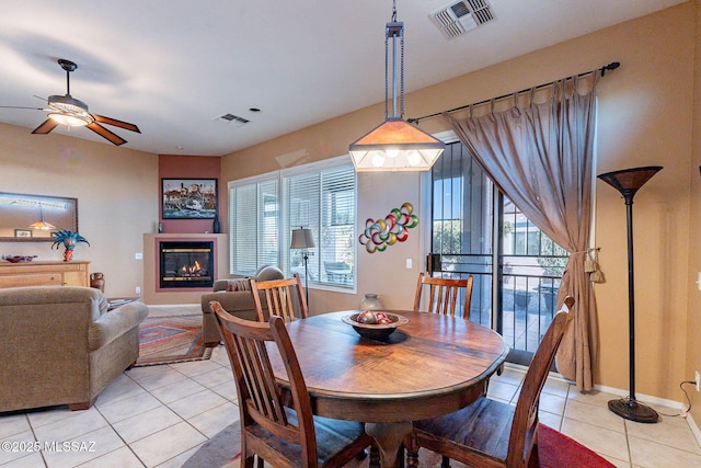 dining area featuring light tile patterned floors, a glass covered fireplace, visible vents, and a healthy amount of sunlight