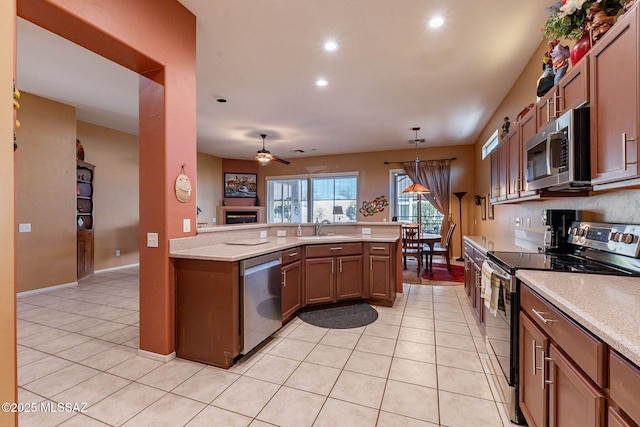 kitchen featuring light tile patterned floors, stainless steel appliances, a sink, and brown cabinets