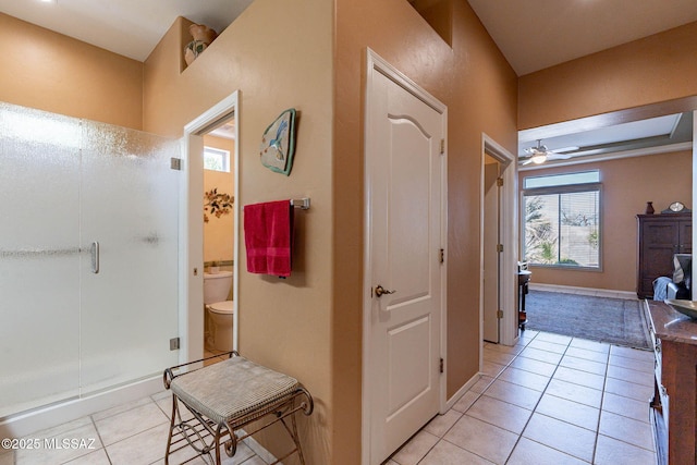 full bathroom featuring toilet, a ceiling fan, a shower stall, tile patterned flooring, and baseboards