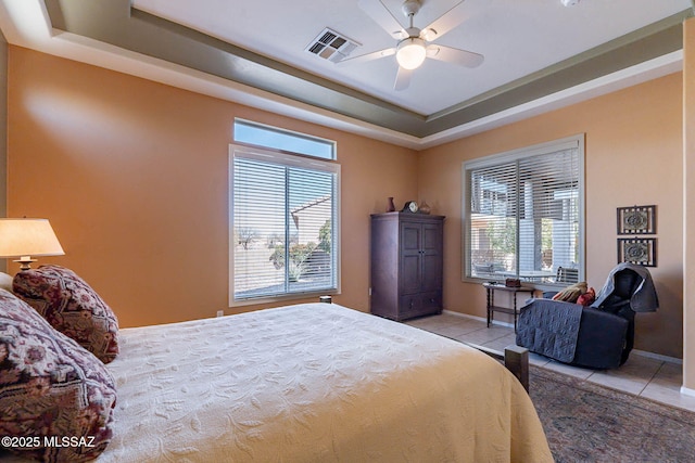 bedroom featuring a tray ceiling, visible vents, baseboards, and light tile patterned floors