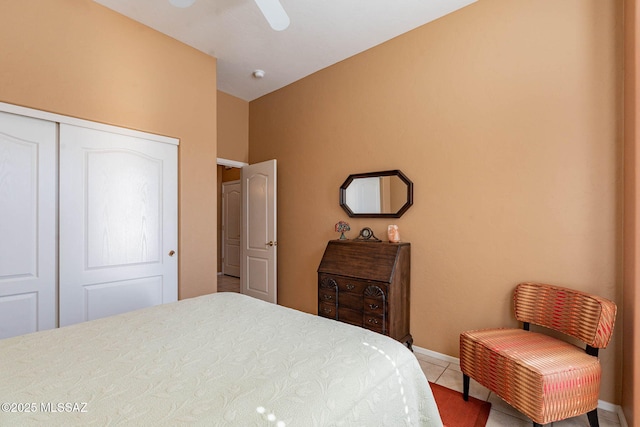 bedroom with light tile patterned floors, ceiling fan, a closet, and baseboards