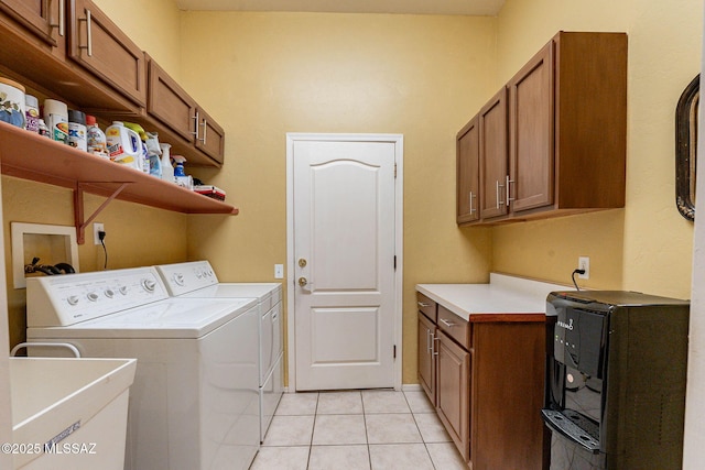 laundry room featuring cabinet space, light tile patterned flooring, a sink, and washing machine and clothes dryer