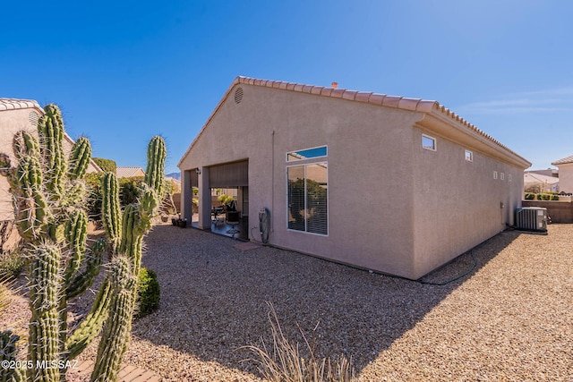 view of home's exterior featuring a patio, central air condition unit, stucco siding, fence, and a tiled roof