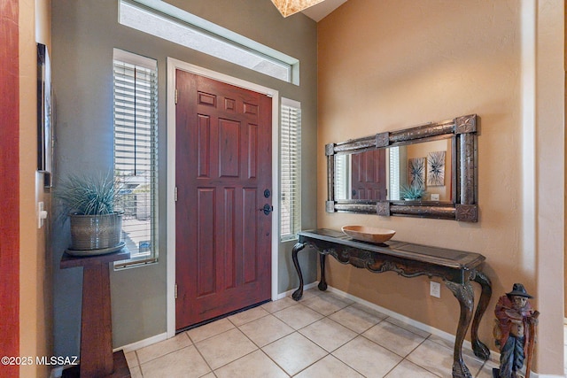 foyer with light tile patterned floors, a wealth of natural light, and baseboards