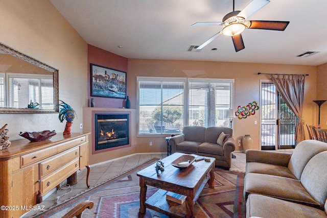 living room with light tile patterned flooring, a glass covered fireplace, visible vents, and a healthy amount of sunlight