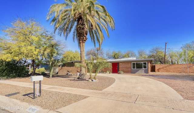 view of front facade with fence, concrete driveway, and brick siding