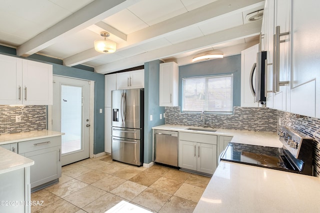 kitchen featuring beam ceiling, appliances with stainless steel finishes, light countertops, and a sink