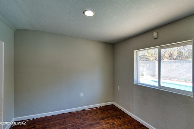 unfurnished room with dark wood-style floors, baseboards, and a textured ceiling