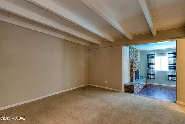 empty room featuring carpet, a fireplace, beamed ceiling, and baseboards