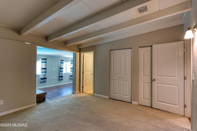 unfurnished bedroom with baseboards, visible vents, beam ceiling, carpet floors, and two closets