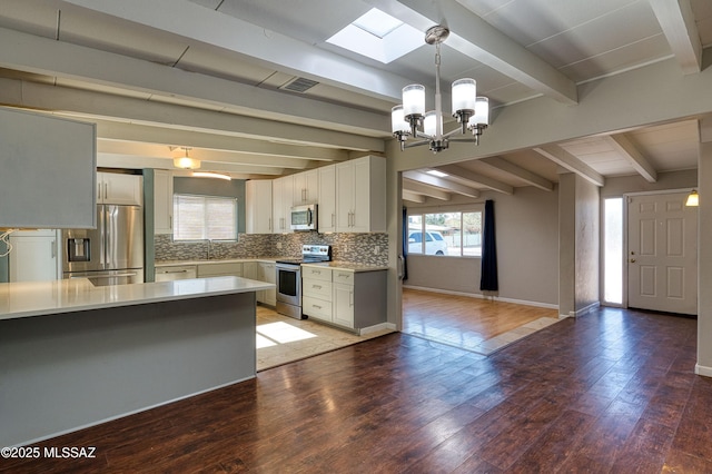 kitchen featuring stainless steel appliances, light countertops, light wood-style floors, and decorative backsplash