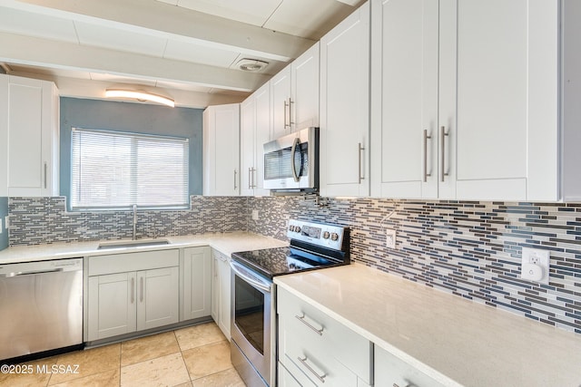 kitchen with light countertops, appliances with stainless steel finishes, backsplash, and a sink