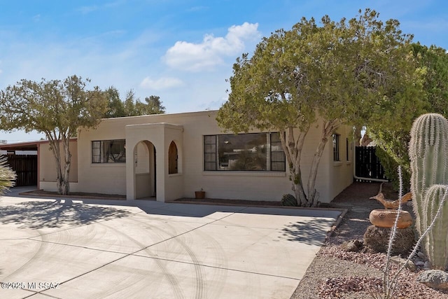 adobe home featuring a patio, fence, and stucco siding