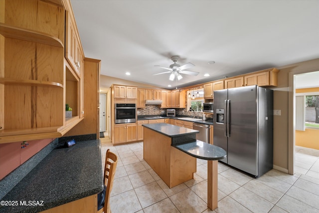 kitchen with a sink, light tile patterned floors, under cabinet range hood, and stainless steel appliances