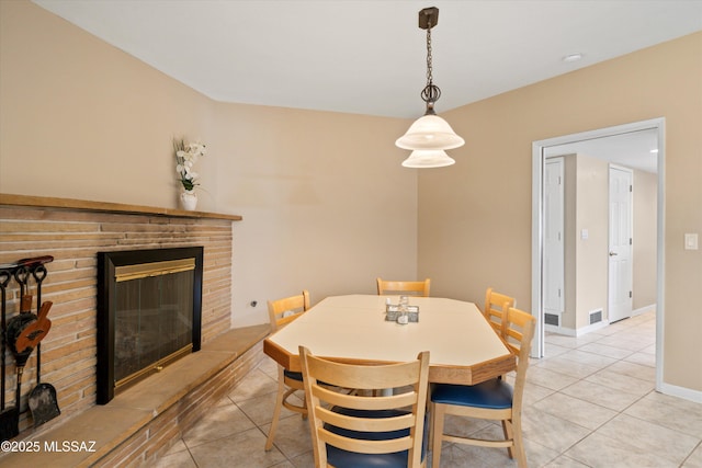 dining space with visible vents, light tile patterned flooring, a fireplace, and baseboards