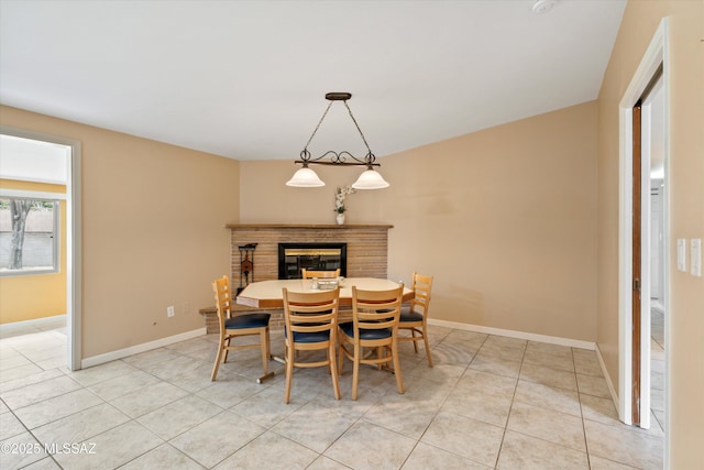 dining space with a glass covered fireplace, light tile patterned floors, and baseboards