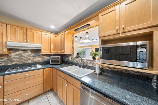 kitchen featuring under cabinet range hood, a sink, tasteful backsplash, dark countertops, and stainless steel appliances