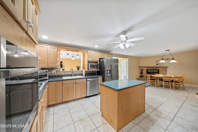 kitchen with light brown cabinetry, a sink, stainless steel appliances, a fireplace, and light tile patterned floors