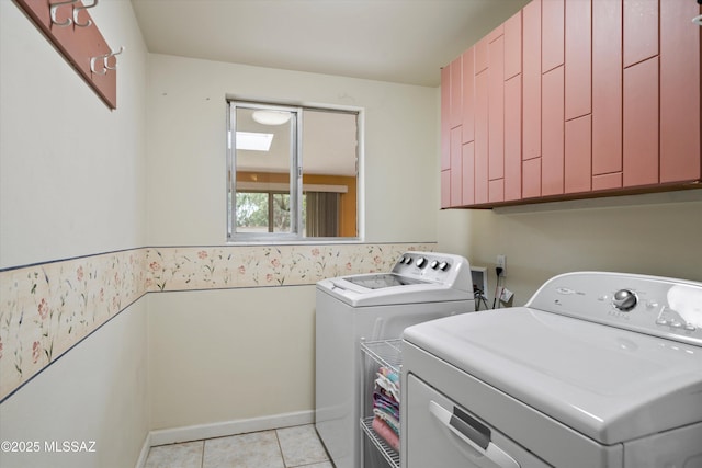 laundry room featuring washing machine and clothes dryer, light tile patterned floors, and cabinet space