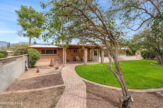 back of property featuring a patio area, brick siding, a yard, and fence