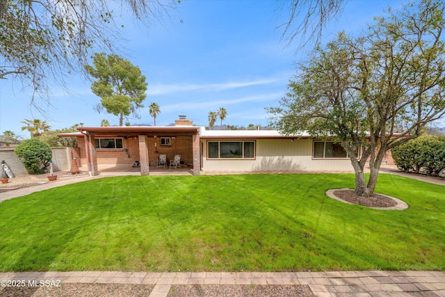 rear view of property with a yard, a patio, and a chimney