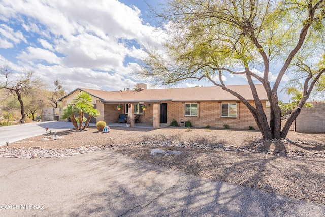 single story home with a garage, concrete driveway, brick siding, and fence