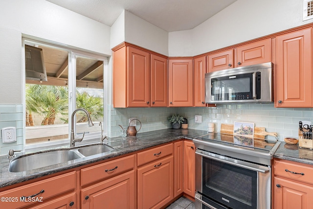 kitchen featuring appliances with stainless steel finishes, backsplash, dark stone countertops, and a sink