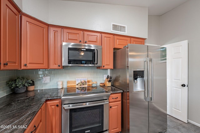 kitchen with dark stone countertops, visible vents, stainless steel appliances, and backsplash