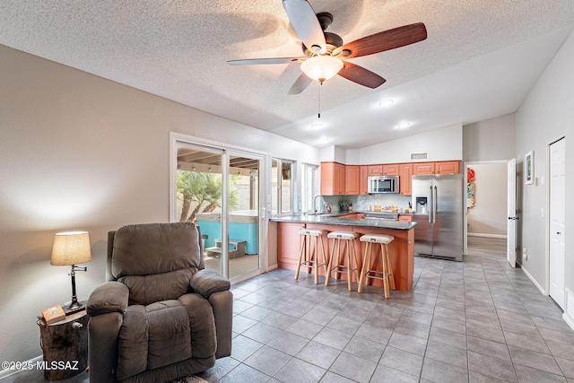 kitchen featuring stainless steel appliances, a peninsula, a sink, vaulted ceiling, and open floor plan