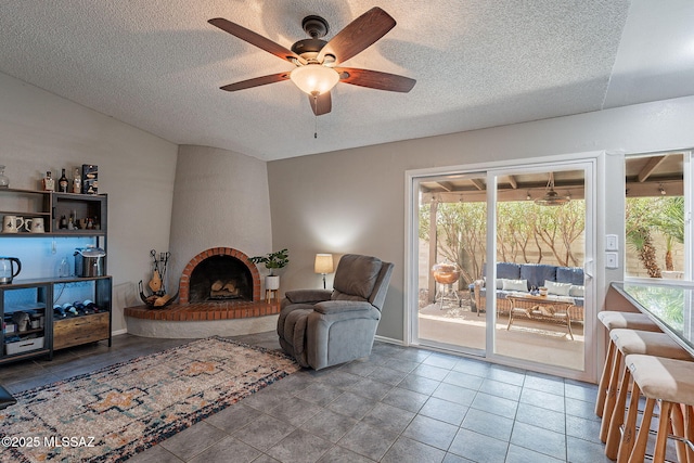 tiled living room with a textured ceiling, plenty of natural light, a fireplace, and a ceiling fan