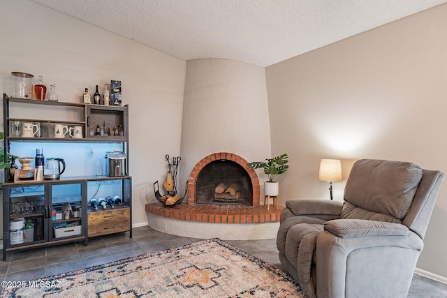 living area featuring a brick fireplace, baseboards, and a textured ceiling