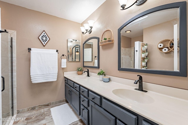 full bath with a tile shower, double vanity, a sink, and baseboards