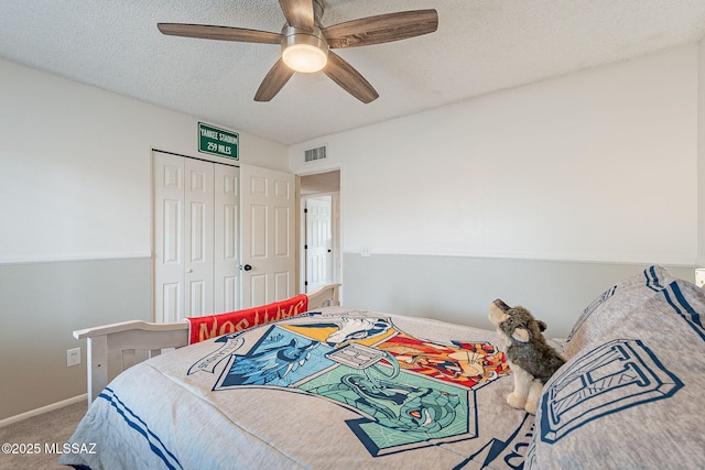 bedroom with carpet floors, a closet, visible vents, a ceiling fan, and a textured ceiling