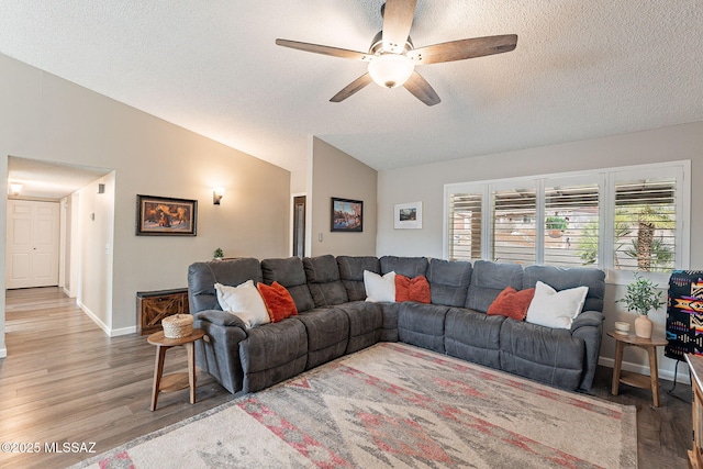 living room featuring baseboards, a ceiling fan, lofted ceiling, wood finished floors, and a textured ceiling