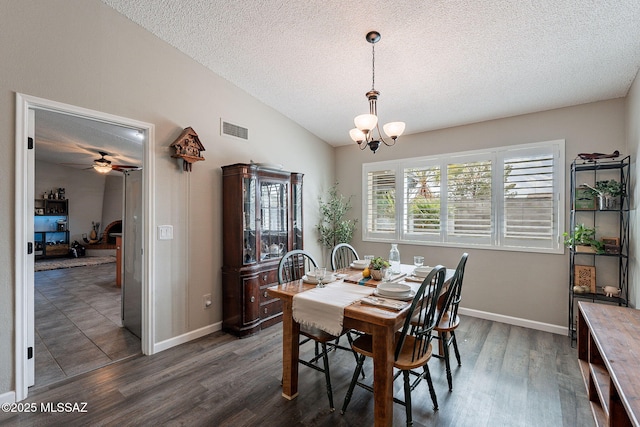 dining space with dark wood-type flooring, lofted ceiling, visible vents, and a textured ceiling