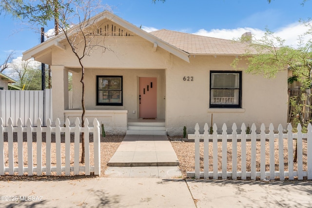 view of front of property with a tiled roof, fence, and stucco siding