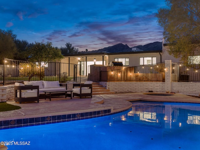 pool at dusk featuring a patio, fence, a fenced in pool, and an outdoor hangout area