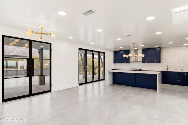 kitchen featuring blue cabinets, backsplash, light countertops, concrete flooring, and a chandelier