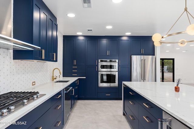 kitchen with blue cabinetry, stainless steel appliances, wall chimney range hood, and a sink