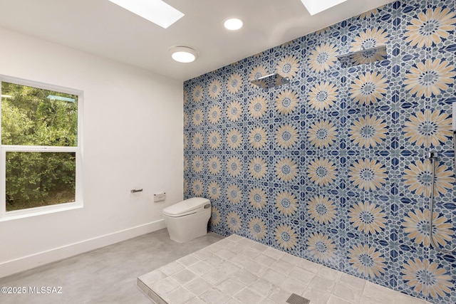 bathroom featuring baseboards, toilet, and a skylight