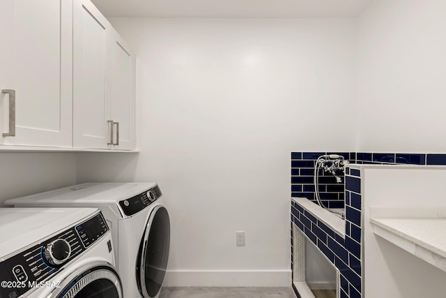 clothes washing area with baseboards, cabinet space, and washer and clothes dryer