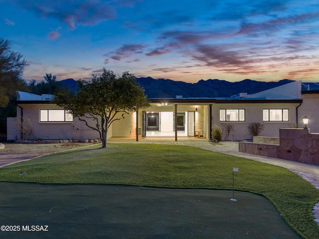 ranch-style home featuring a mountain view and a lawn