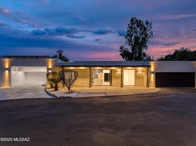 view of front facade with a garage, concrete driveway, and stucco siding