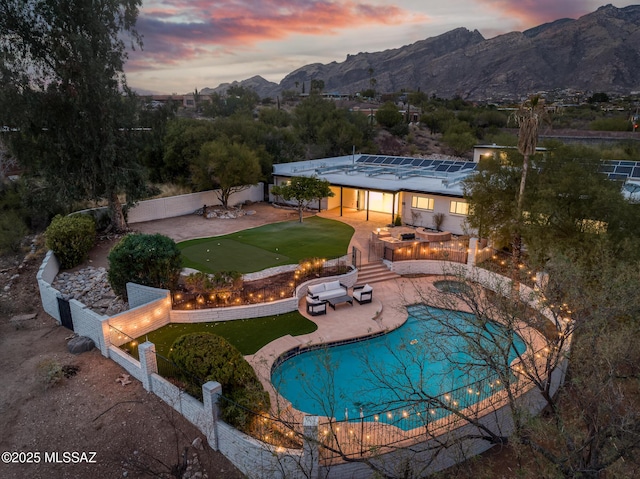 pool at dusk featuring a mountain view, a fenced in pool, fence private yard, and a patio area