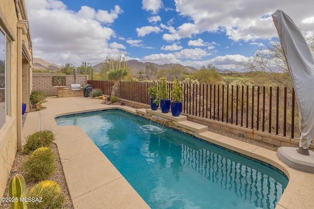 view of pool featuring a patio area, a fenced in pool, a mountain view, and a fenced backyard